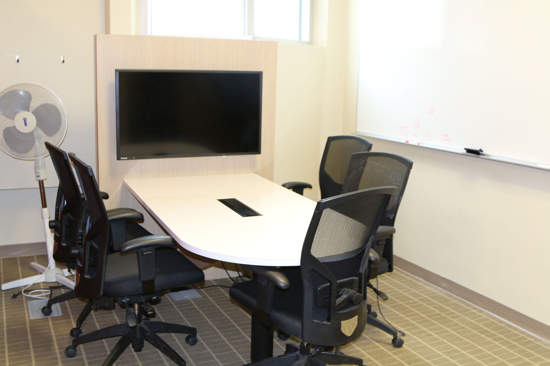 Table and chairs with TV monitor showing a collaborative workspace.
