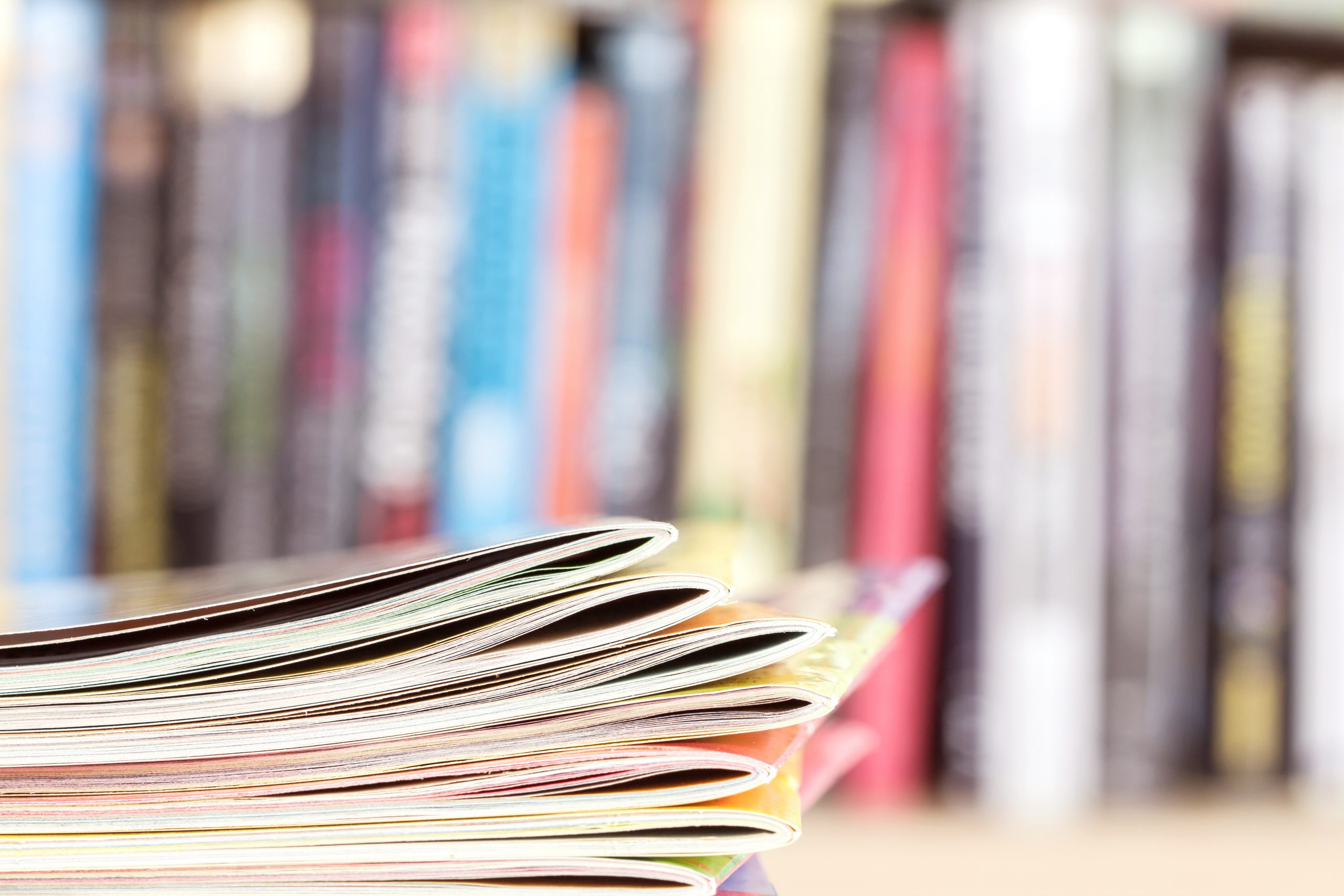 colorful magazine stacking with blurry bookshelf