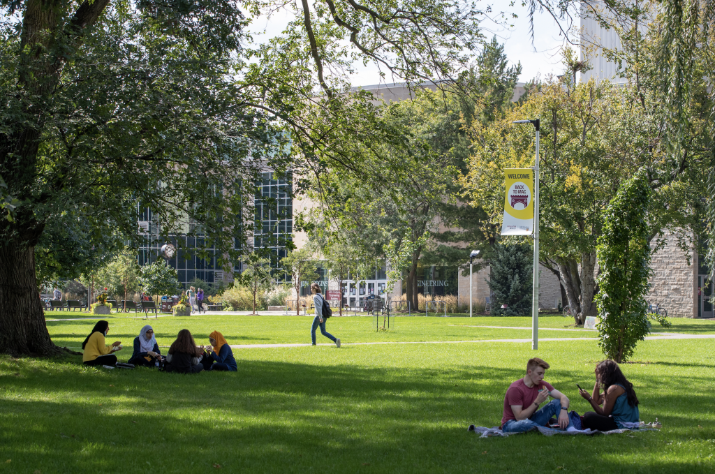 Students sitting on lawn in front of Engineering building at McMaster University