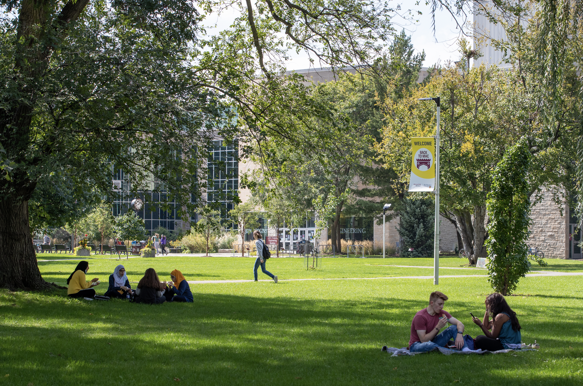 Students sitting on lawn in front of Engineering building at McMaster University