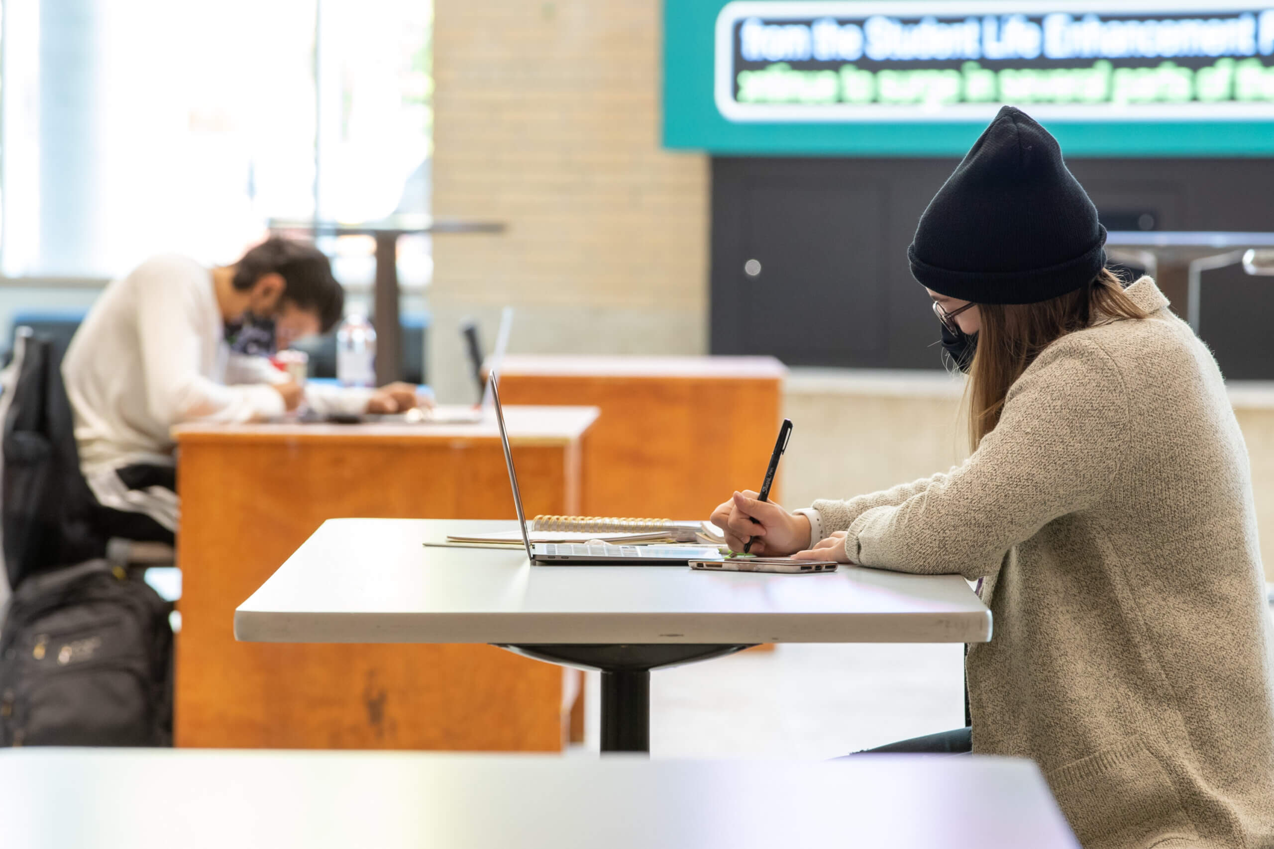 Photo of Student wearing covid mask sitting at dek and taking notes