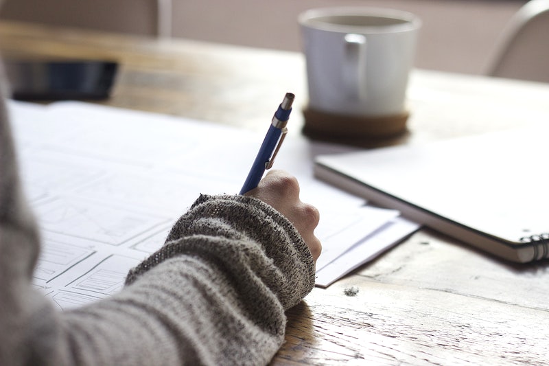 Student writing with a pen on paper