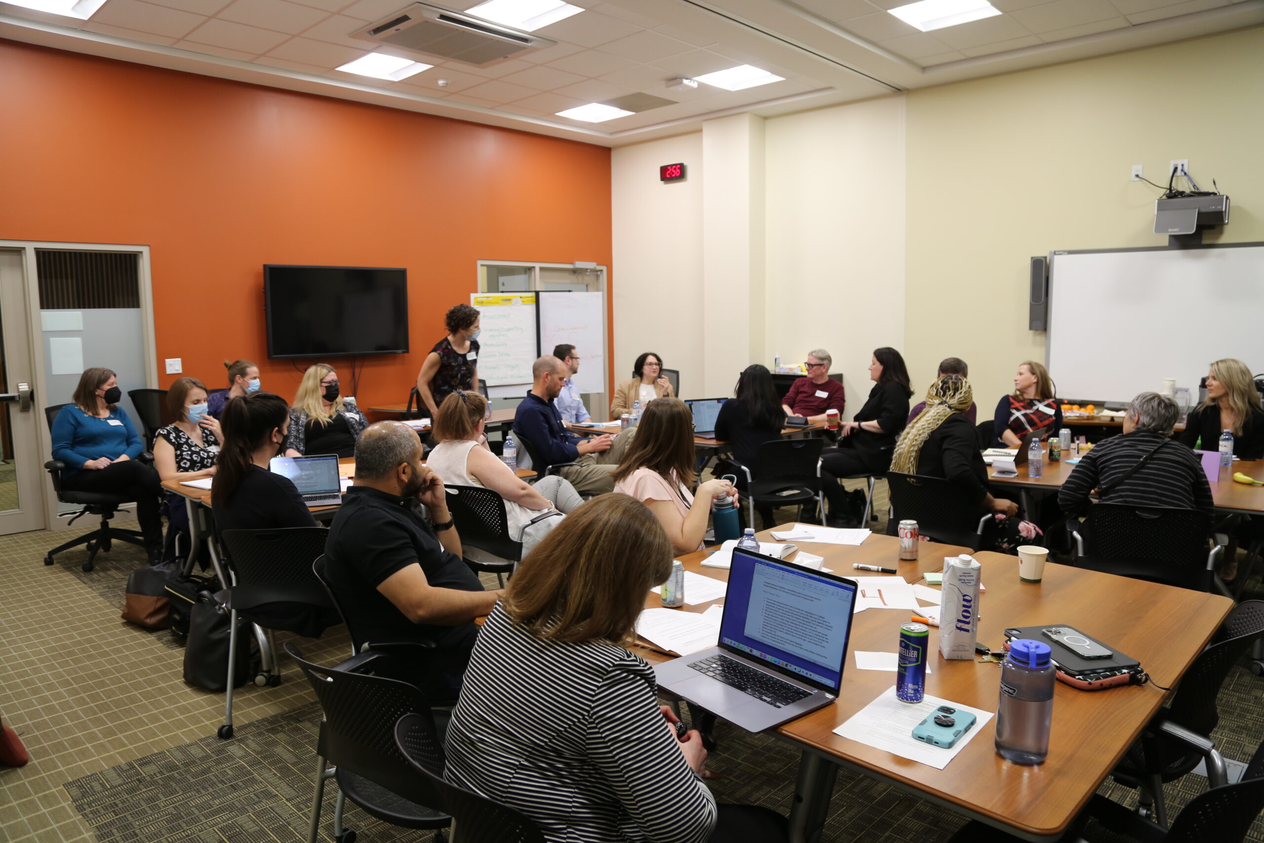 Image of a full classroom of people sitting at laptops and taking notes and talking.