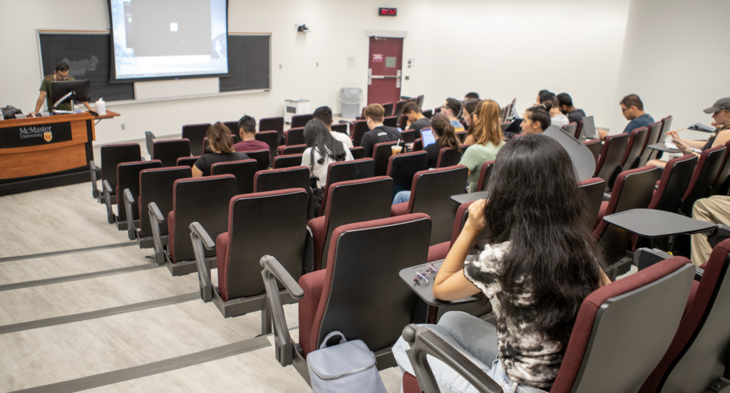 McMaster University lecture hall with instructor at the front of the room and students sitting taking notes